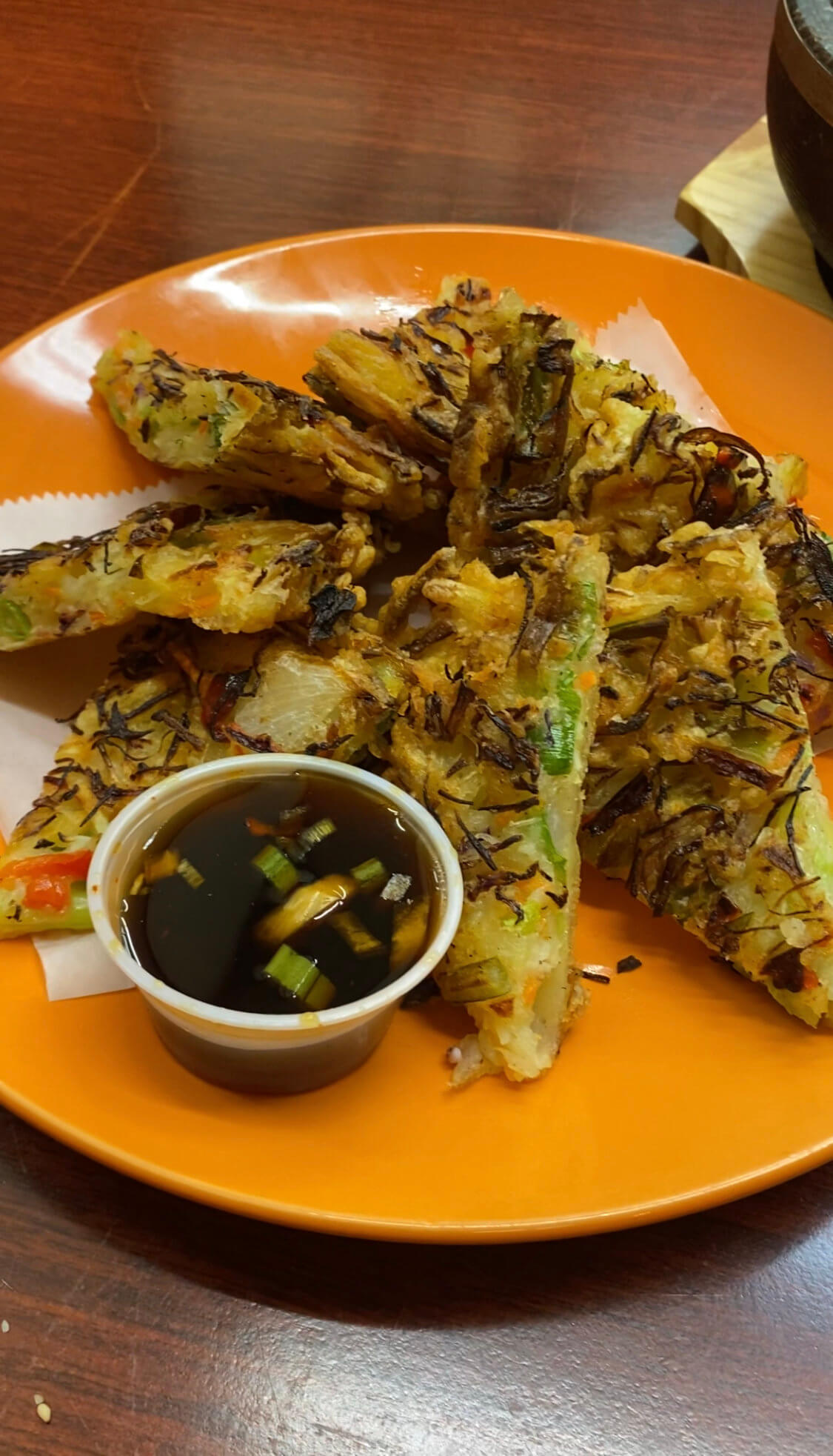 An order of Korean Vegetable Pancakes, Yachaejeon, with a side of soy dipping sauce.