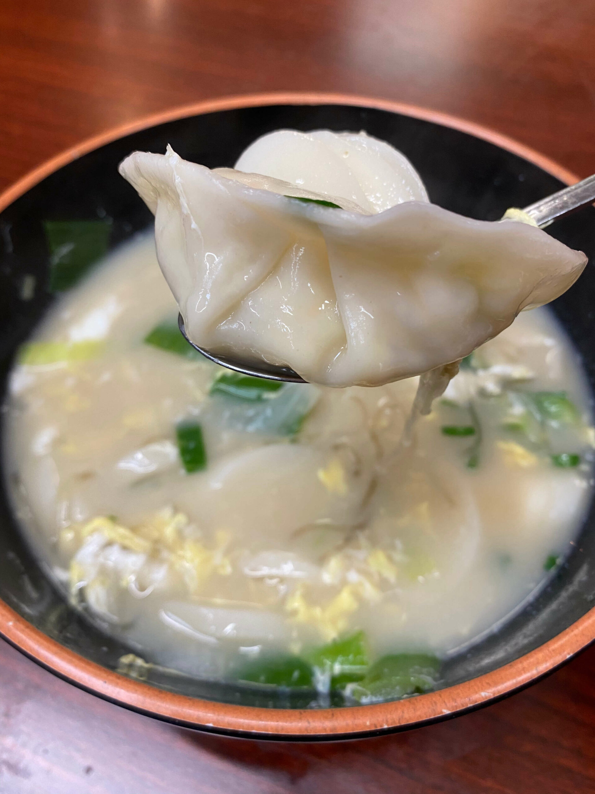 Kimchi Mama’s rice cake and dumpling soup with a dumpling on the spoon